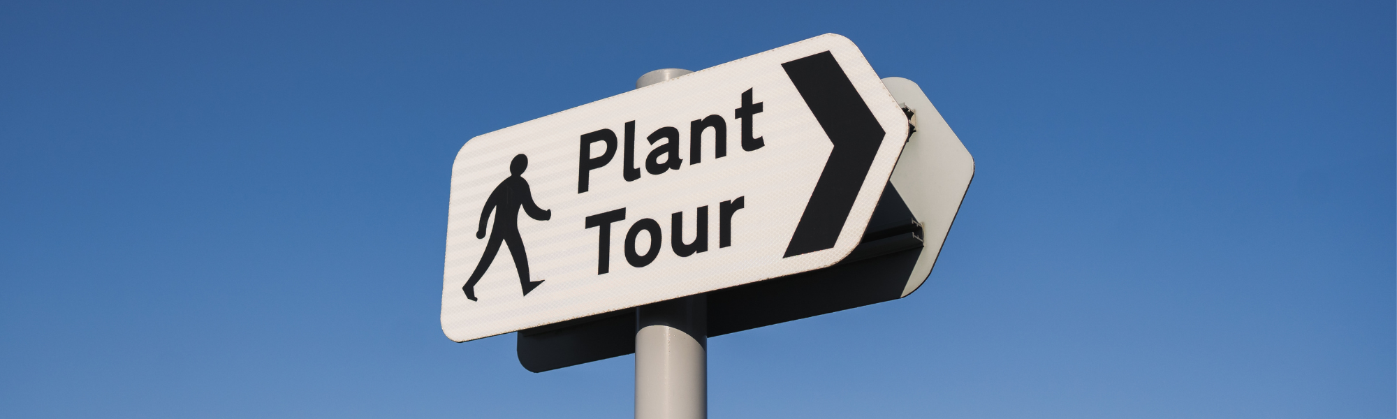 Auf einem Straßenschild in Pfeilform ist die Aufschrift Plant Tour zu lesen. Außerdem ist auf dem Schild ein Icon von einem Männchen, das in Richtung der Tour läuft
